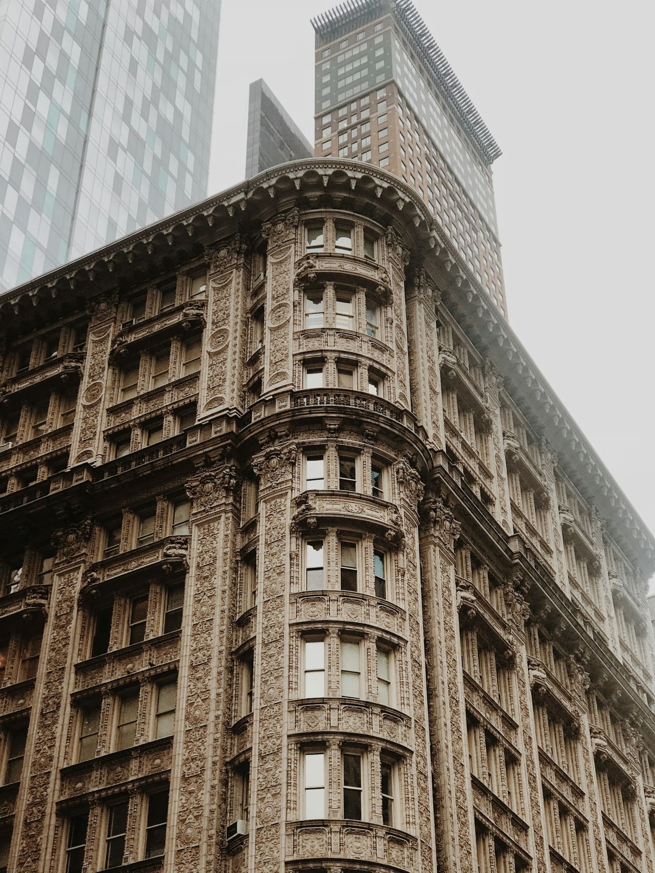 Ornate terracotta facade of Alwyn Court, a 1909 prewar apartment building in Manhattan, with modern towers rising behind it